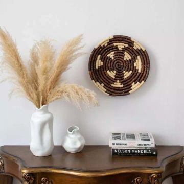 Brown handwoven wall basket styled on an elegant wooden console with ceramic vases and pampas grass perfect for bohemian and rustic home décor.