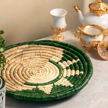 Handwoven bamboo wall decor plate in green beige tones displayed with pampas vase enhancing modern boho interior.