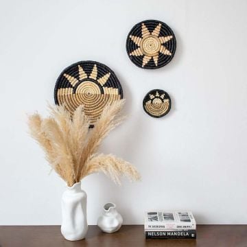 Black and beige bamboo wall plates displayed above wooden console with pampas vase creating modern rustic wall decor.