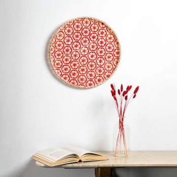 Bamboo woven wall basket with red geometric pattern creating vibrant bohemian texture accent in minimalist interior design.