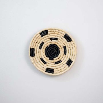 Woven basket photographed on a clean white background featuring a round handwoven design in natural and black tones showcasing artisan weaving details.