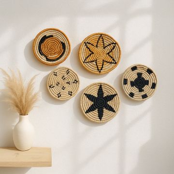 Set of handwoven jute wall basket decor in beige black and brown star and spiral designs styled on white wall for boho living room.