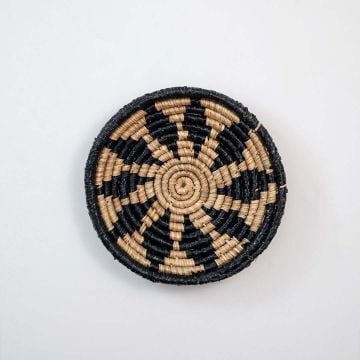 Handwoven wicker wall plate round in beige and black natural fiber spiral design light on white background for boho decor.