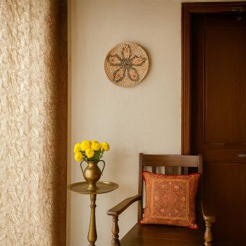 Handwoven wicker wall plate decor in natural beige with black and orange pattern styled on wall in cozy living space.