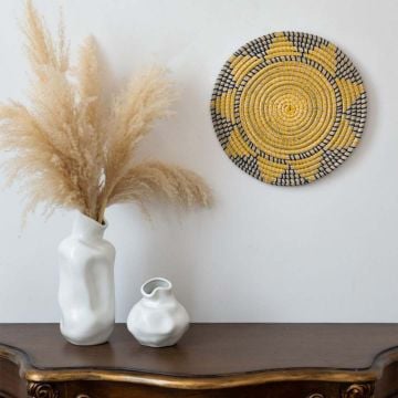 Round wicker wall plate handmade in yellow navy and beige woven pattern perfect for modern boho wall decoration.