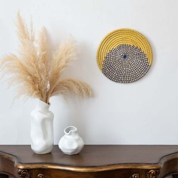 Handwoven wicker wall plate decor in yellow navy and beige half circle design styled on wall with boho home accents.