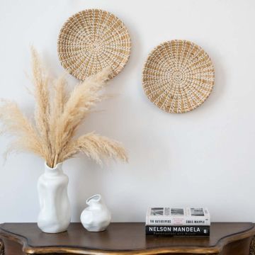 Handwoven wicker basket wall decor with natural beige and white woven starburst pattern for boho modern interiors.