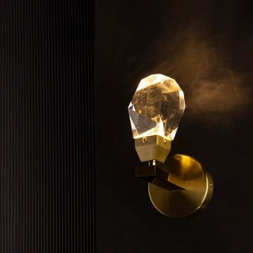 Crystal and gold wall sconce glowing on white background enhancing elegance and adding charm to modern decor.