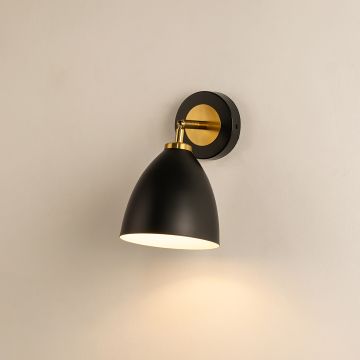 A modern black metal wall light glowing softly against a beige wall creating warm illumination and stylish contemporary sconce décor for modern interiors.