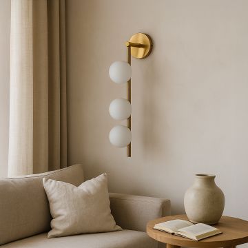 Elegant gold wall sconce with three frosted glass globes creating warm cozy ambiance in modern living room interior above sofa décor.