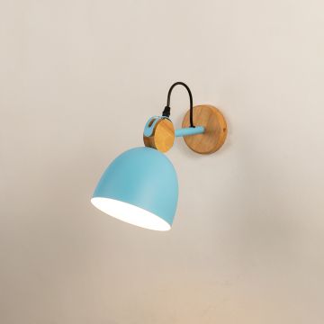 A blue Scandinavian wall light with a matte dome shade and wooden mount shown with the light on against a clean white background giving a warm soft glow.