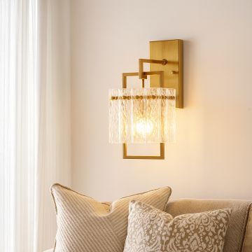 Elegant gold wall sconce with textured glass shade glowing warmly above sofa in modern living room creating cozy interior décor.