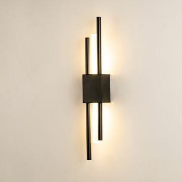 A black wall sconce with tall vertical rods and a glowing acrylic tube shown with lights on against a white background highlighting its warm modern illumination.