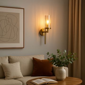 Elegant gold wall sconce with ribbed glass shade glowing warmly in modern living room beside sofa wall art and indoor plant.