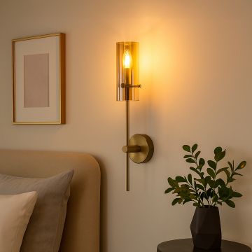 Modern gold wall light with glass shade glowing warmly beside bed creating cozy bedroom ambiance with elegant home décor.
