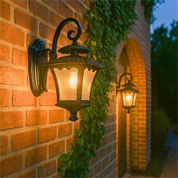 Decorative lantern wall sconce casting warm light along a traditional brick pathway with ivy accents.