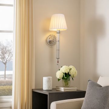 Modern wall light with fabric shade glowing beside sofa vase and curtains in bright living room decor.