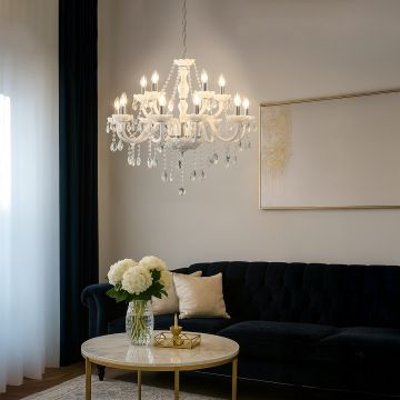 White crystal chandelier glowing warmly in modern living room with dark sofa gold table and elegant wall decor.