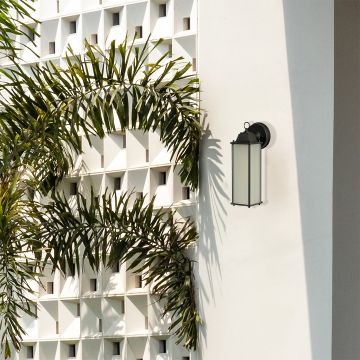 Black outdoor wall lantern styled in a minimal lifestyle setting showcasing its tall frosted glass panel and sleek metal frame.
