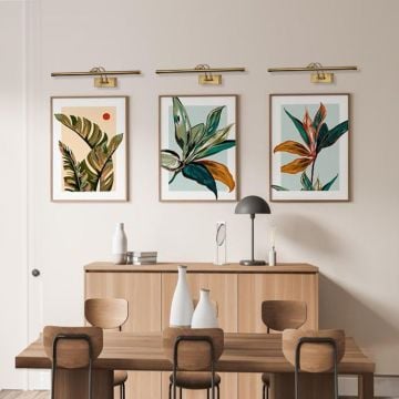 Gold metal picture lights styled together on a modern wall creating warm balanced gallery style accent illumination.