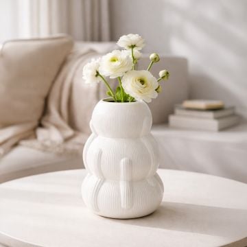 White ceramic sculpted decorative vase with fresh flowers styled on coffee table enhancing soft and contemporary home decor.