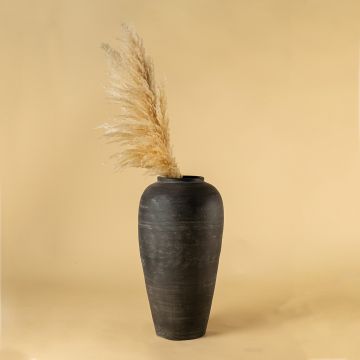 Tall matte black terracotta vase styled in a warm interior adding sleek handcrafted depth and modern earthy elegance to contemporary home decor styling.