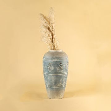 Tall blue carved terracotta vase styled in a warm interior adding handcrafted charm and elegant detailing to modern natural home decor styling.