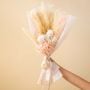 Elegant dried flower bouquet with pampas grass infinity rose hydrangea and babysbreath tied with satin ribbon on plain background.