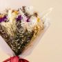 Closeup of preserved dried flowers with purple infinity rose white sunflower crystal grass and fern leaves in natural tones.