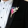 Artificial boutonniere flower with pink blue and white preserved stems on black background creating a decorative dried flower.