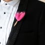 Groom boutonniere featuring bold pink feather style with jute wrap shown on black background perfect for modern wedding decor.