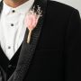 Boutonniere with pink fabric flower and delicate dried grass wrapped in jute displayed on black background.