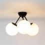 Black ceiling light with three glowing frosted glass globes on sleek frame displayed on white background for home lighting.