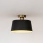 Black ceiling light with gold fitting and drum shade glowing warmly displayed on white background for modern ceiling decor.