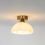 Gold ceiling light with white dome shade glowing warm on white background for stylish home lighting.