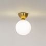 Gold ceiling light with frosted glass globe shade glowing warmly on plain white background for home lighting.