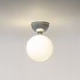 Chrome ceiling light with frosted glass globe shade glowing warmly on plain white background for home lighting.