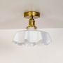 White glass ceiling light with gold metal mount displayed on an off white background showing clean elegant design.