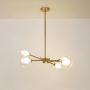 Gold sputnik chandelier with clear glass sphere shades turned off on white background showing mid-century modern fixture.