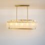 Illuminated gold rectangular chandelier with crystal droplets on white background showcasing luxury dining room light fixture.