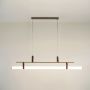Gold linear pendant light with glowing white tube diffuser on a clean white background showing sleek modern design.