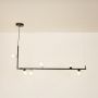 Black linear chandelier with clear glass globes illuminated on a white background showing its modern design.