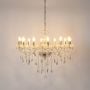 Crystal chandelier with gold detailing illuminated on white background highlighting elegant luxury light fixture.