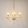 Crystal chandelier with gold finish illuminated on white background highlighting luxury lighting design.