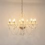 Crystal chandelier with gold finish glowing warmly on white background to highlight luxury interior style.