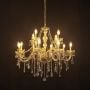 Chandelier with gold frame and crystal drops illuminated against black background for elegant home decor.
