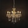 Elegant chandelier with silver frame and crystal droplets illuminated against black background for decor.