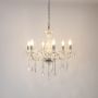 Crystal chandelier with silver base glowing brightly on white background highlighting luxury light design.