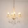 Chandelier with crystal and gold design illuminated on white background highlighting elegant interior lighting.