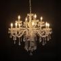 Elegant chandelier with crystal and gold accents illuminated against black background for stylish luxury lighting.